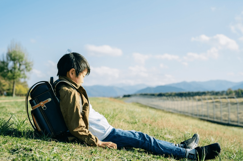 土手に座る小学生の男の子